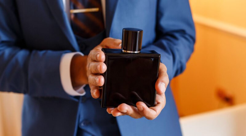 successful-man-blue-formal-suit-holding-hands-expensive-black-bottle-perfumes