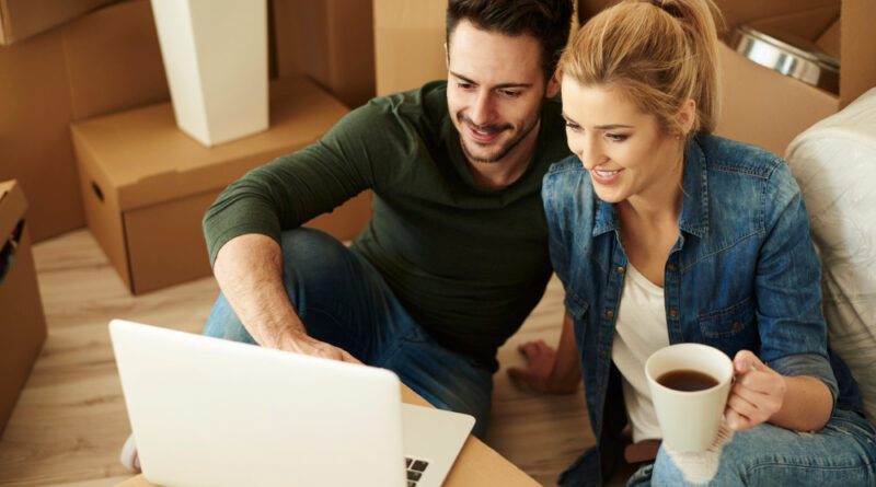 Beautiful Couple Using Laptop Among Cartons