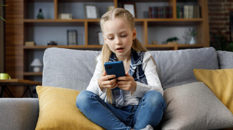 portrait-cute-little-cute-girl-holding-smartphone-resting-sofa-home-choosing-favorite-music-cartoonstexting-messagesbrowsing-internetwatching-video-playing-games-mobile-phone