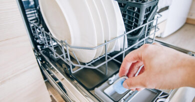 woman-hand-putting-tablet-dishwasher-detergent-box-dishwasher-machine-full-loaded-closeup