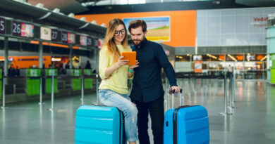 Young Girl With Long Hair Yellow Sweater Jeans Is Sitting Suitcase Airport Guy With Beard Black Shirt With Pants Suitcase Is Standing Near They Are Looking Tablet