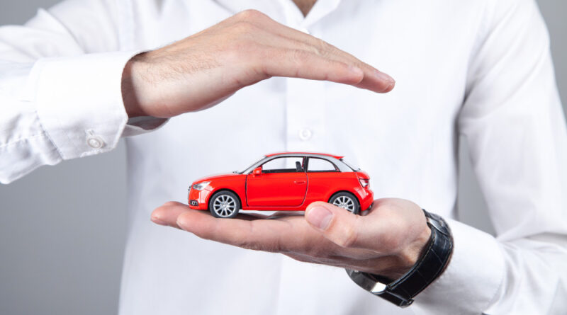 male-hands-protect-red-toy-car