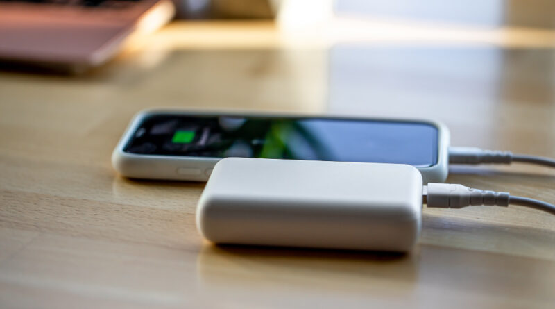 Smartphone Is Charged From Small White Power Bank Via Cord