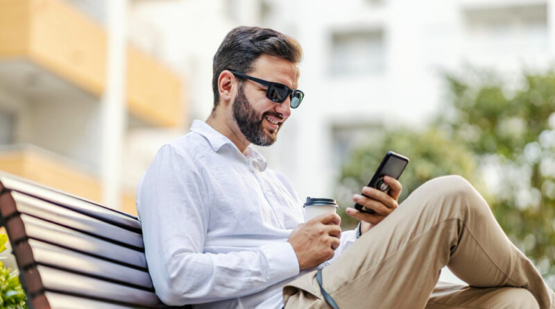 Happy Businessman With Sunglasses Is Sitting Bench Park Holding Coffee Using Apps