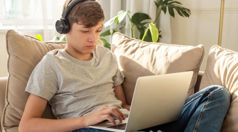 Portrait Teenage Sits Sofa Room Wearing Black Headphones His Head Using Laptop