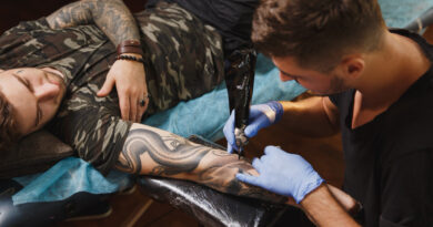 professional-tattooer-artist-doing-tattoo-arm-young-man-by-machine-with-black-ink