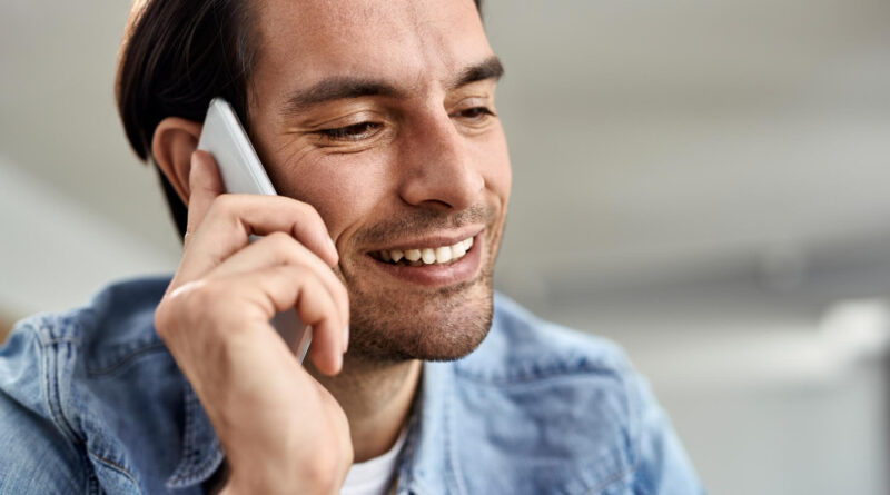 Young Happy Man Using Smart Phone While Making Phone Call Home