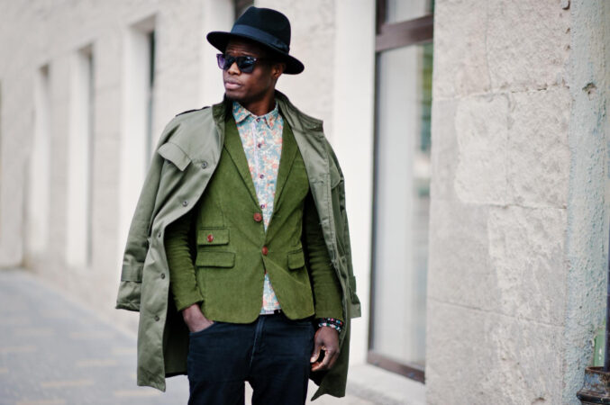 fashion-portrait-black-african-american-man-green-velvet-jacket-black-hat-coat-cloak-his-shoulders-walking-streets-city-background-house-with-many-windows