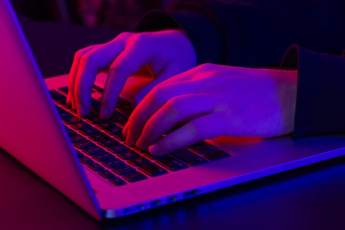 man-uses-laptop-closeup-male-hands-neon-lighting