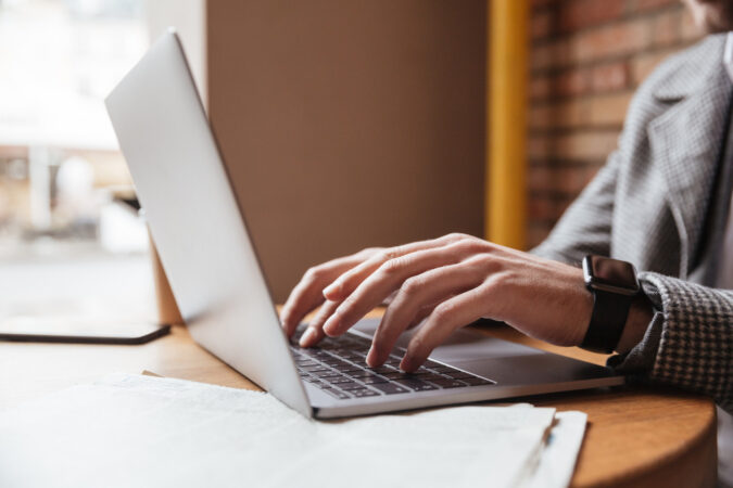 cropped-image-businessman-eyeglasses-sitting-by-table-cafe-using-laptop-computer