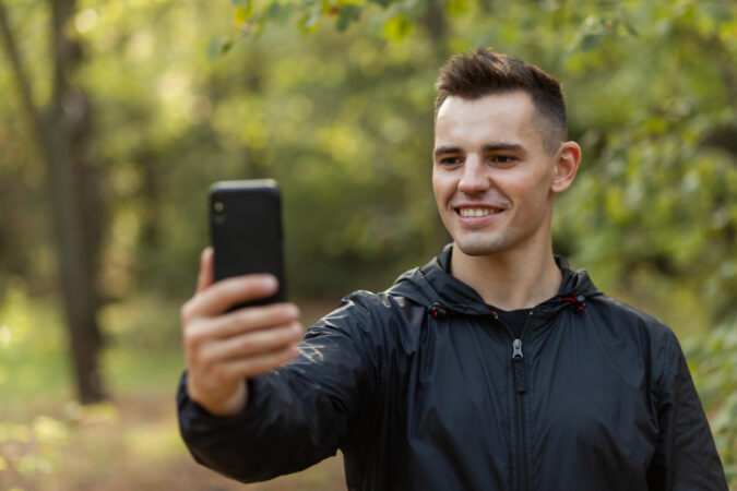 handsome-man-taking-selfie-phone-autumn-forest