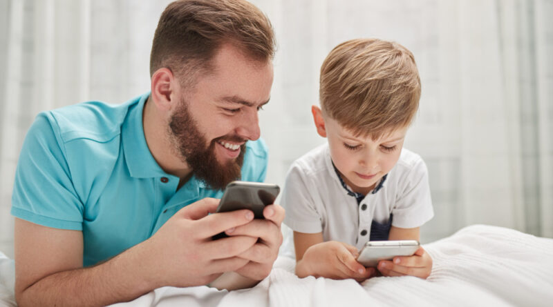 Father Son Using Gadgets Bedroom