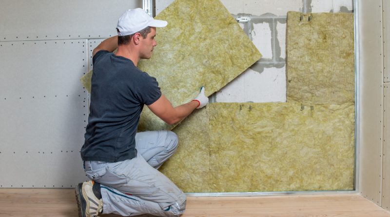 Worker insulating room wall with mineral rock wool thermal insulation