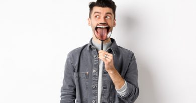 handsome-positive-guy-showing-white-perfect-teeth-tongue-with-magnifying-glass-looking-left-logo-standing-against-white-background