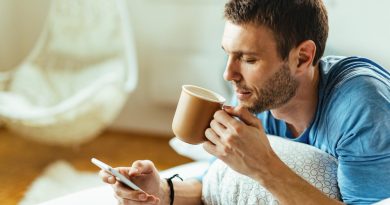 Young Man Texting Phone While Drinking Morning Coffee Bed