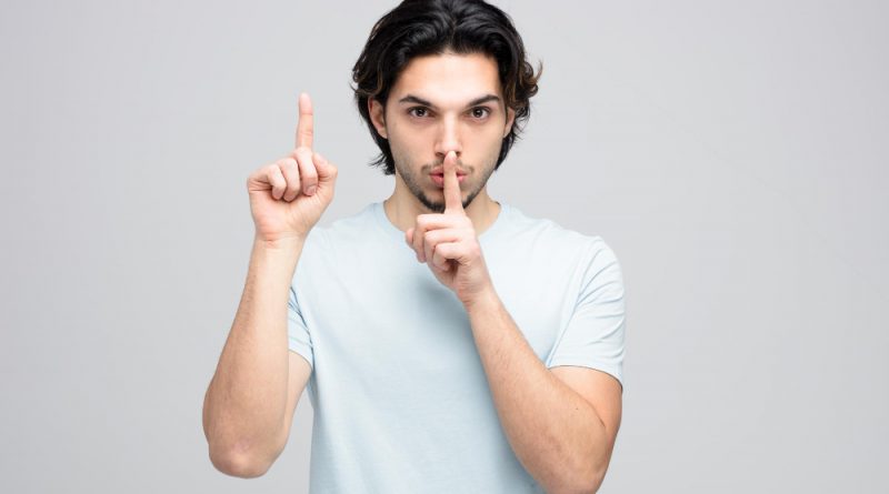 Serious Young Handsome Man Looking Camera Showing Silence Gesture Pointing Up Isolated White Background