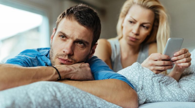 Displeased Man Lying Bed Ignoring His Girlfriend Who Is Text Messaging Mobile Phone