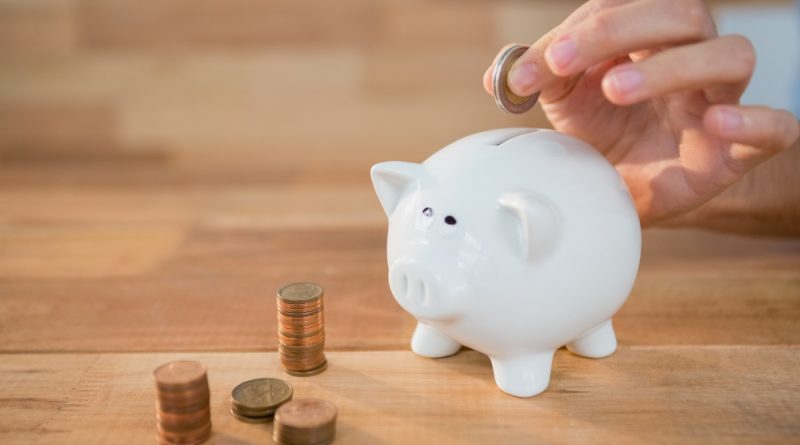 Hand Inserting Coin Piggy Bank