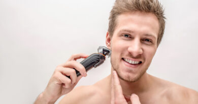 Cheerful Young Man Shaving With Machine