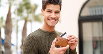 Young Caucasian Man Outdoors Holding Wallet Credit Card With Happy Expression