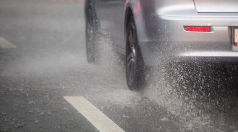 Rain Water Splash Flow From Wheels Silver Car Moving Fast Daylight City With Selective Focus