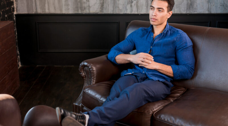Young Man Sitting Sofa With His Crossed Legs Hand Clasped Looking Away