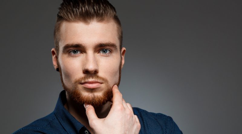 Young successful businessman posing dark wall