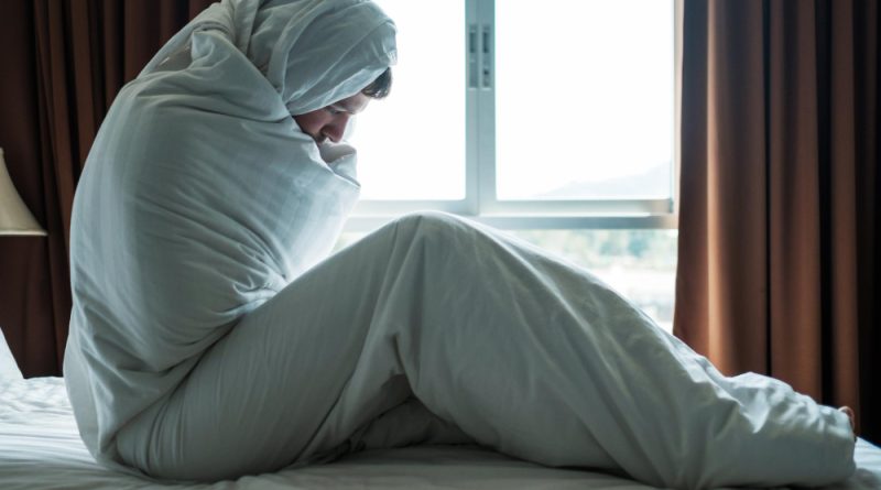 Depressed man sitting his bed covered with blanket looking window he is depressed after divorce