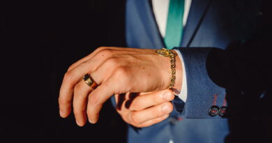 A Man Clasps A Gold Bracelet On His Arm. Hands Of Successful Businessman In Tuxedo, Closeup. Men's Accessories, Bracelet And Gold Ring On A Man's Hand.