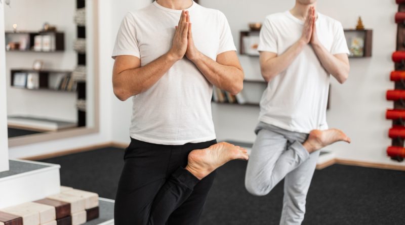 Two guys stand one leg meditate fitness class young men practice yoga poses