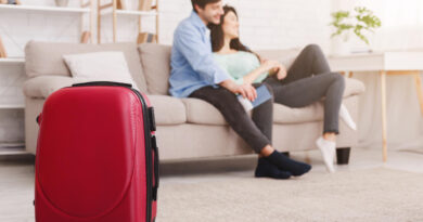 Couple Relaxing Sofa With Suitcase Foreground
