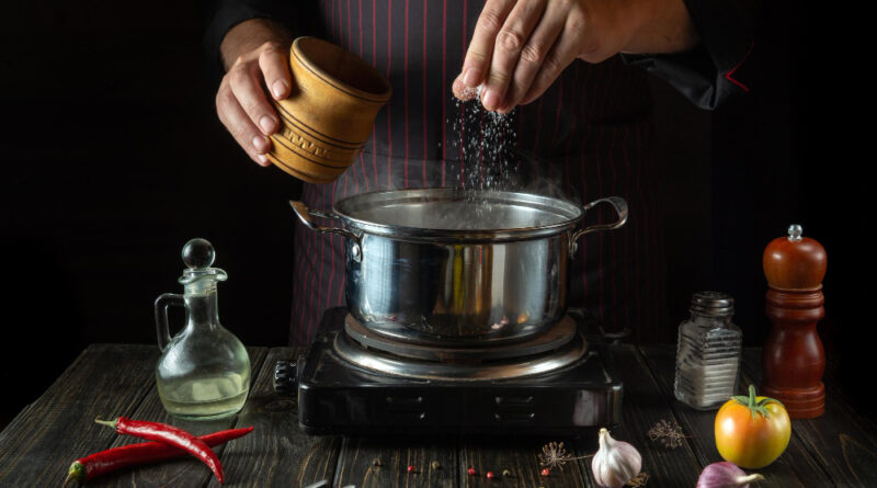 Chef adds salt pot hot food cooking diet lunch kitchen hotel restaurant