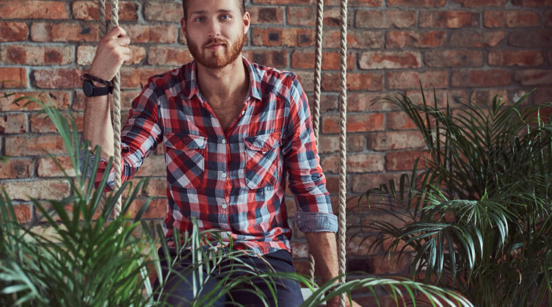 Young Handsome Redhead Model Man Sits Swing Room With Loft Interior