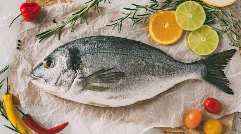 Top view sea gilt head bream fish baking sheet with rosemary lemon orange tomato