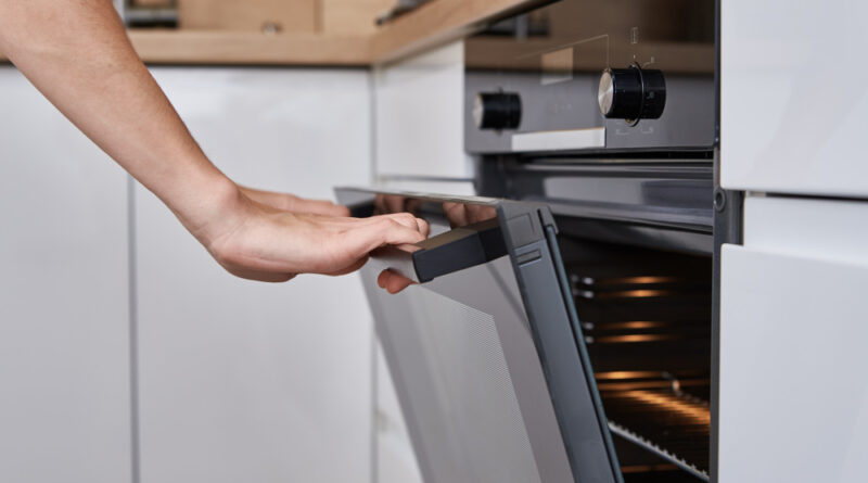 Woman hand open electric oven door with handle homemade cooking kitchen appliance