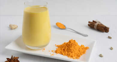 drinking-glass-full-golden-milk-served-plate-with-turmeric-powder-wooden-table