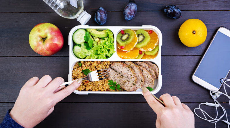 Top view showing hands eating healthy lunch with bulgur meat fresh vegetables fruit wooden table fitness healthy lifestyle concept lunchbox top view