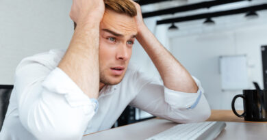 upset-disappointed-young-businessman-sitting-workplace-with-hands-head