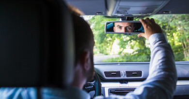 man-sitting-inside-car-adjusting-rear-view-mirror